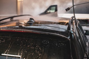 Arabasını yıkayan bir adam. Arabasıyla ilgilenen genç bir çocuk..