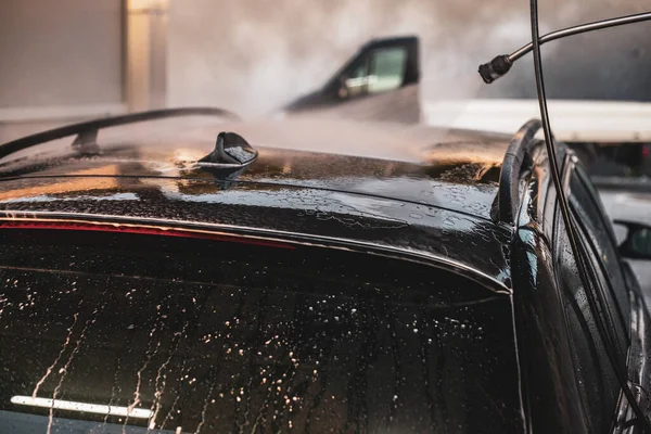 A man washing his car. A young boy taking care of his car.