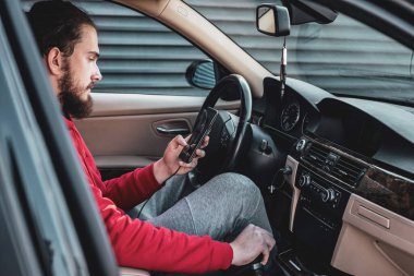 Genç bir çocuk yeni temizlenmiş arabada telefonunu kullanıyor.. 