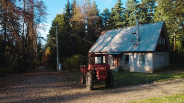 Ormandaki çiftçi evinin yanındaki eski kırmızı traktör.