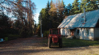 Ormandaki çiftçi evinin yanındaki eski kırmızı traktör.