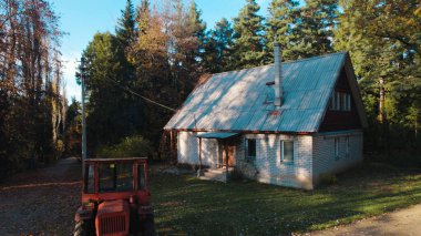 Ormandaki çiftçi evinin yanındaki eski kırmızı traktör.