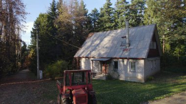 Ormandaki çiftçi evinin yanındaki eski kırmızı traktör.