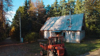 Ormandaki çiftçi evinin yanındaki eski kırmızı traktör.