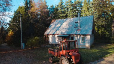 Ormandaki çiftçi evinin yanındaki eski kırmızı traktör.