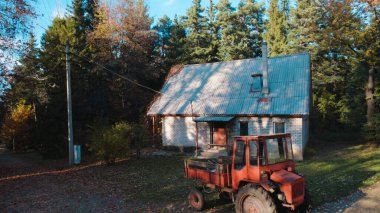 Ormandaki çiftçi evinin yanındaki eski kırmızı traktör.