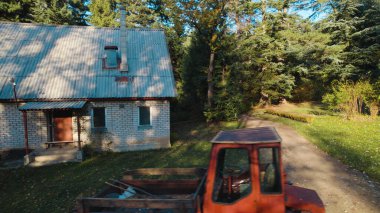 Ormandaki çiftçi evinin yanındaki eski kırmızı traktör.