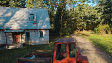 Ormandaki çiftçi evinin yanındaki eski kırmızı traktör.