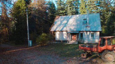 Ormandaki çiftçi evinin yanındaki eski kırmızı traktör.