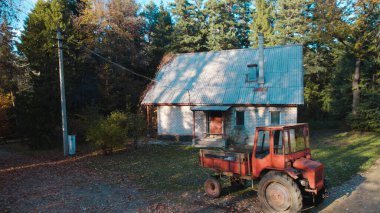 Ormandaki çiftçi evinin yanındaki eski kırmızı traktör.