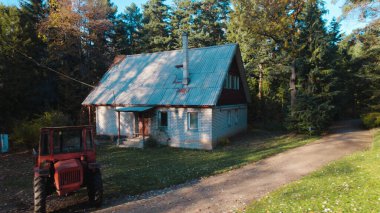 Ormandaki çiftçi evinin yanındaki eski kırmızı traktör.