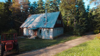 Ormandaki çiftçi evinin yanındaki eski kırmızı traktör.