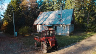 Ormandaki çiftçi evinin yanındaki eski kırmızı traktör.