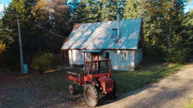 Ormandaki çiftçi evinin yanındaki eski kırmızı traktör.