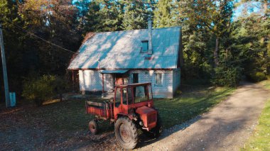 Ormandaki çiftçi evinin yanındaki eski kırmızı traktör.