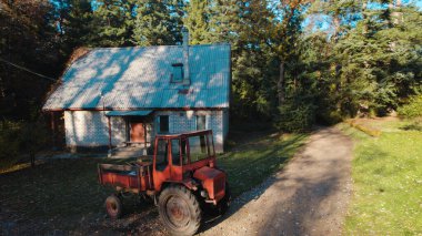 Ormandaki çiftçi evinin yanındaki eski kırmızı traktör.