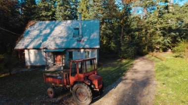 Ormandaki çiftçi evinin yanındaki eski kırmızı traktör.