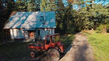 Ormandaki çiftçi evinin yanındaki eski kırmızı traktör.