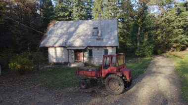 Ormandaki çiftçi evinin yanındaki eski kırmızı traktör.