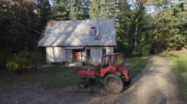 Ormandaki çiftçi evinin yanındaki eski kırmızı traktör.