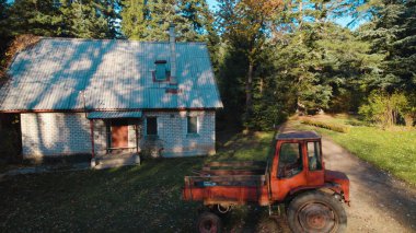 Ormandaki çiftçi evinin yanındaki eski kırmızı traktör.