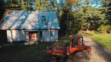 Ormandaki çiftçi evinin yanındaki eski kırmızı traktör.