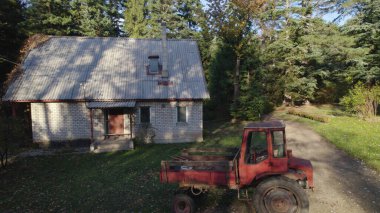 Ormandaki çiftçi evinin yanındaki eski kırmızı traktör.