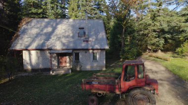 Ormandaki çiftçi evinin yanındaki eski kırmızı traktör.