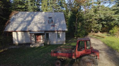 Ormandaki çiftçi evinin yanındaki eski kırmızı traktör.