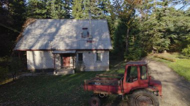 Ormandaki çiftçi evinin yanındaki eski kırmızı traktör.