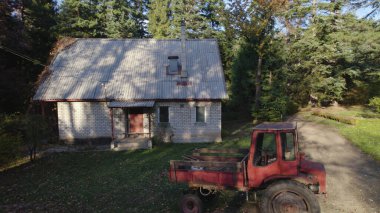 Ormandaki çiftçi evinin yanındaki eski kırmızı traktör.