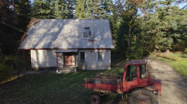 Ormandaki çiftçi evinin yanındaki eski kırmızı traktör.