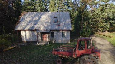 Ormandaki çiftçi evinin yanındaki eski kırmızı traktör.