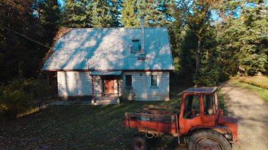 Ormandaki çiftçi evinin yanındaki eski kırmızı traktör.