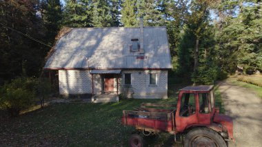 Ormandaki çiftçi evinin yanındaki eski kırmızı traktör.