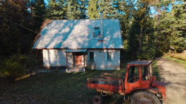 Ormandaki çiftçi evinin yanındaki eski kırmızı traktör.