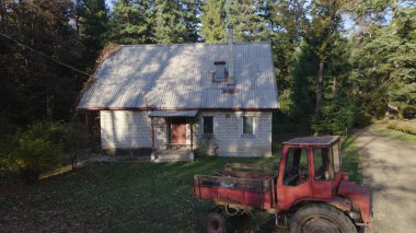 Ormandaki çiftçi evinin yanındaki eski kırmızı traktör.