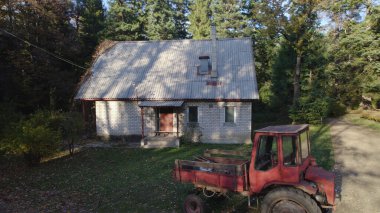 Ormandaki çiftçi evinin yanındaki eski kırmızı traktör.