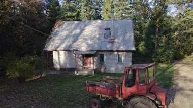 Ormandaki çiftçi evinin yanındaki eski kırmızı traktör.