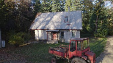 Ormandaki çiftçi evinin yanındaki eski kırmızı traktör.