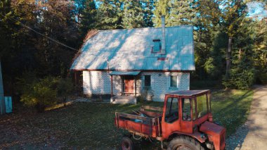 Ormandaki çiftçi evinin yanındaki eski kırmızı traktör.