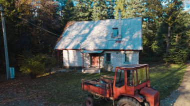 Ormandaki çiftçi evinin yanındaki eski kırmızı traktör.