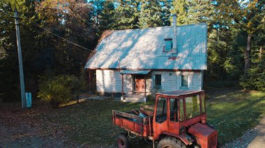 Ormandaki çiftçi evinin yanındaki eski kırmızı traktör.