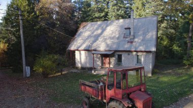 Ormandaki çiftçi evinin yanındaki eski kırmızı traktör.