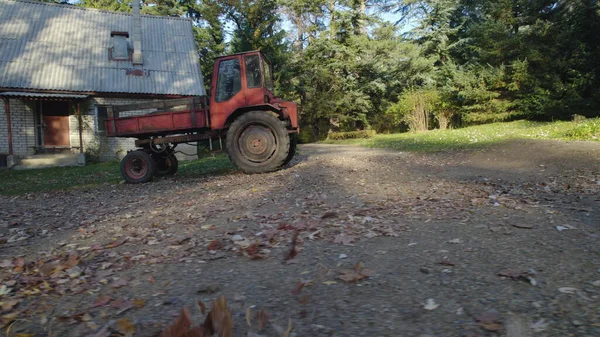 森林里靠近农舍的红色旧拖拉机 — 图库照片