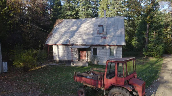 Ormandaki çiftçi evinin yanındaki eski kırmızı traktör.