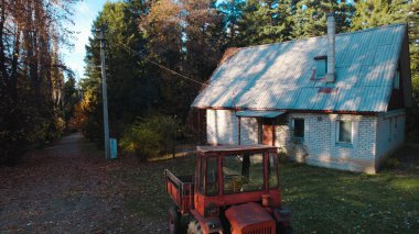 Ormandaki çiftçi evinin yanındaki eski kırmızı traktör.