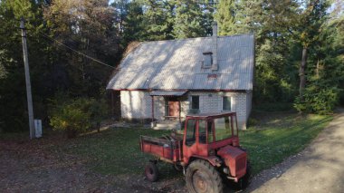 Ormandaki çiftçi evinin yanındaki eski kırmızı traktör.