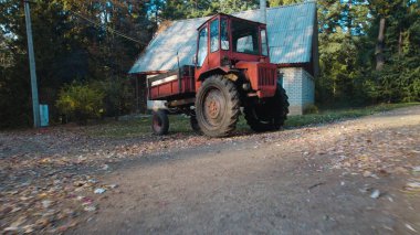 Ormandaki çiftçi evinin yanındaki eski kırmızı traktör.