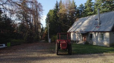 Ormandaki çiftçi evinin yanındaki eski kırmızı traktör.